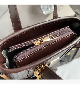 Detail view of smooth golden zipper and brown lychee grain leather on the luxury tote bag