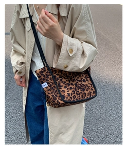 Détail d'un sac cabas léopard en toile avec sangle en corde noire et étiquette latérale