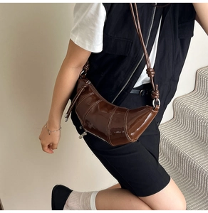 Detail view of deep chocolate brown patent leather croissant bag with knotted strap