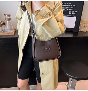 Detailed view of deep brown pebbled leather shoulder bag in a stylish half-moon shape