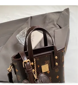 Detailed macro view of the golden metal logo plate on a brown textured leather bucket bag