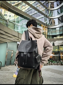 Close-up of black PU leather backpack with drawstring closure and metal buckle on street