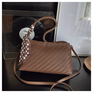 Close-up of brown woven shoulder bag with silk scarf detail and round woven handle