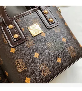 Close-up of brown textured handbag featuring diamond bear prints and gold metal rivets