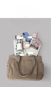 Top view of khaki nylon tote bag showing spacious interior with magazine and water bottle