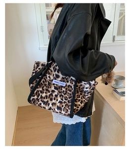Détail du grand sac cabas à motif léopard avec poignée en sangle noire et logo blanc