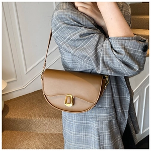 Close-up of brown faux leather saddle bag with gold ring buckle on a grey plaid suit