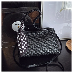 Detail of woven texture black hobo bag with a polka dot scarf on a vintage vinyl background