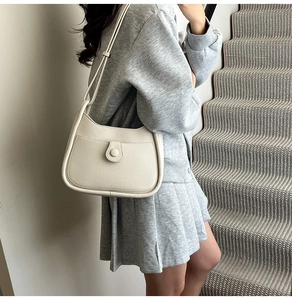 Detailed side view of cream hobo shoulder bag with litchi texture and front pocket