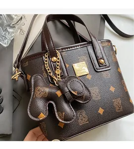 Detail of lychee pattern brown leather bucket bag with monogram bear print and gold chain