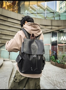 Detailed view of a black vintage leather backpack with drawstring closure and side pockets