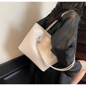 Detail of minimalist cream tote bag with litchi texture leather and gold branding
