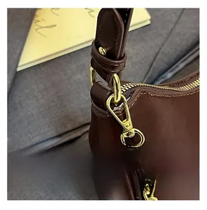 Detail of dark brown leather shoulder bag featuring gold-tone hardware and chain link