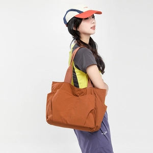 Close-up detail of a brown nylon tote bag with functional outer pockets for extra storage
