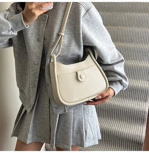 Mirror selfie showing a cream pebble leather bucket bag with front pocket detail