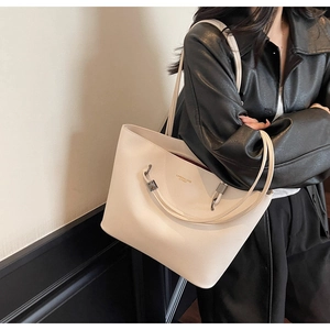 Close-up of cream lychee leather tote bag with silver hardware and logo text on shoulder