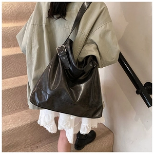Detailed view of glossy black PU hobo bag with wide shoulder strap and silver buckle