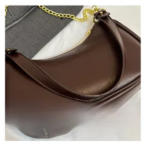 Macro view of dark brown crescent bag showing fine stitching and glossy leather texture