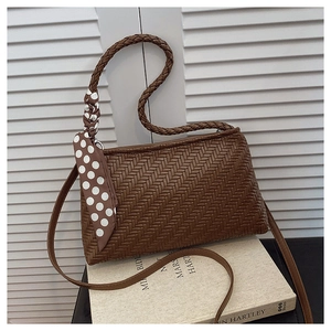 Detailed close-up of brown woven shoulder bag with chic polka dot scarf accessory