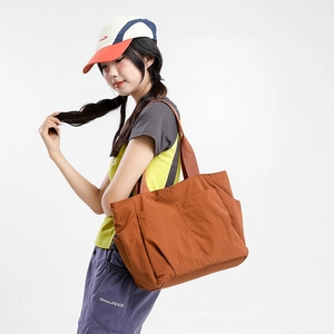 Detail of dark orange large tote bag showing side pocket and durable nylon texture