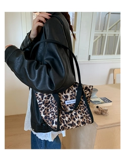 Détail du sac cabas en toile léopard avec poignées noires et étiquette de marque blanche