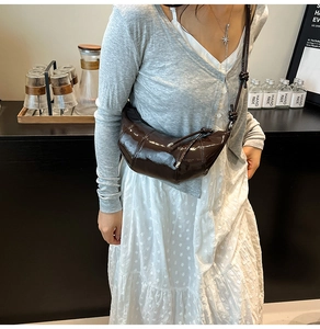 Detail of glossy coffee brown croissant bag with adjustable knotted shoulder strap texture