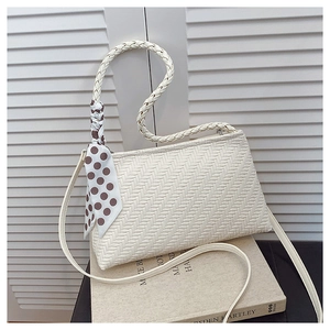 Detailed view of woven texture on a cream shoulder bag with stylish polka dot scarf