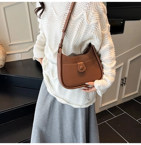 Detailed close-up of brown pebbled leather hobo bag featuring adjustable buckle strap