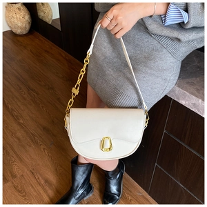 Detail of white saddle bag with golden horseshoe buckle and chain leather strap