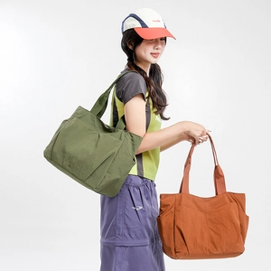 Detail of army green and red large nylon tote bags showing side pockets and lightweight fabric
