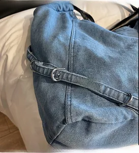 Dettaglio della tracolla in denim con fibbia in metallo argento e cuciture rinforzate
