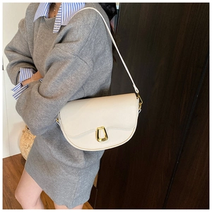 Detailed view of cream half-moon saddle bag with gold metal clasp on model