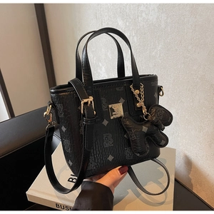 Close-up of black leather bucket bag with bear print and golden brand nameplate