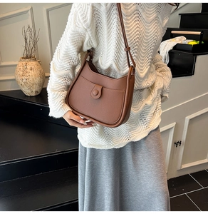 Close-up of brown litchi grain leather shoulder bag with flap closure on model
