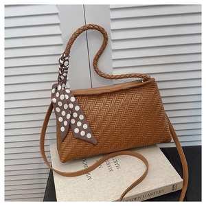 Detail of brown woven hobo bag with polka dot scarf and knotted rope handle texture