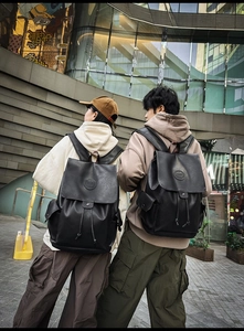 Detail of a vintage black leather backpack with drawstring closure and flip cover design