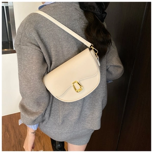Detailed side view of the cream white saddle bag showing smooth leather and gold hardware