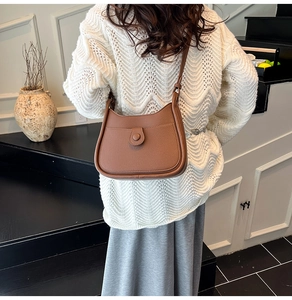 Detailed back view of a brown pebbled leather crescent crossbody bag worn by a model