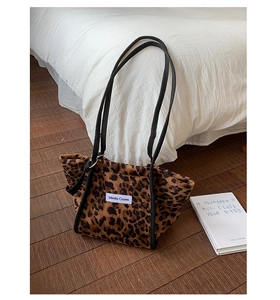 Vue détaillée du sac cabas à motif léopard avec poignées tressées noires sur un sol