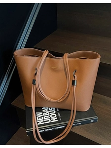 Brown large capacity leather tote bag with Chris & Love logo on wooden stairs