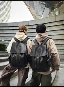 Macro detail of black leather backpack featuring drawstring closure and flap cover design