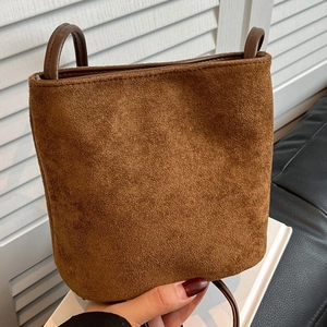 Minimalist brown suede bucket bag with slim shoulder straps and matte finish