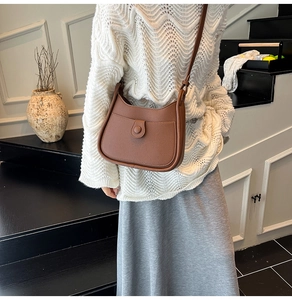 Detail of a brown lychee pattern leather saddle bag with button pocket and shoulder strap