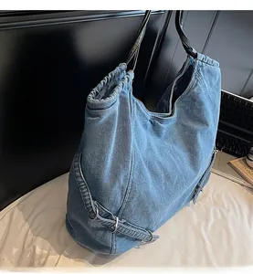 Dettaglio della borsa tote in denim azzurro con tracolla in pelle nera e chiusura a coulisse