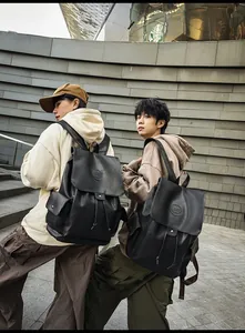 Outdoor urban shot of a large black faux leather backpack with flap and side pockets