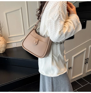 Chic khaki faux leather bucket bag with adjustable strap worn with white sweater