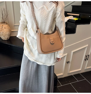 Detail of camel leather hobo bag featuring pebbled texture and front pocket with round clasp