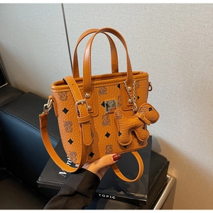 Detail of brown PU leather bucket bag featuring bear monogram and cute dog charm attachment