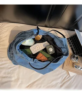 Dettaglio della capienza interna della borsa tote in denim blu con vari oggetti