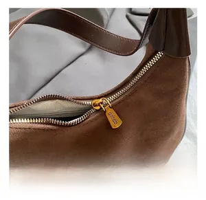 Détail du sac lune en daim marron avec quincaillerie dorée et fermeture éclair de luxe